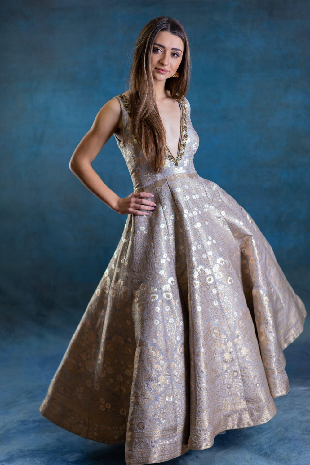 Elegant jacquard silk A-line gown with intricate gold embroidery, deep plunge neckline, and voluminous skirt.
