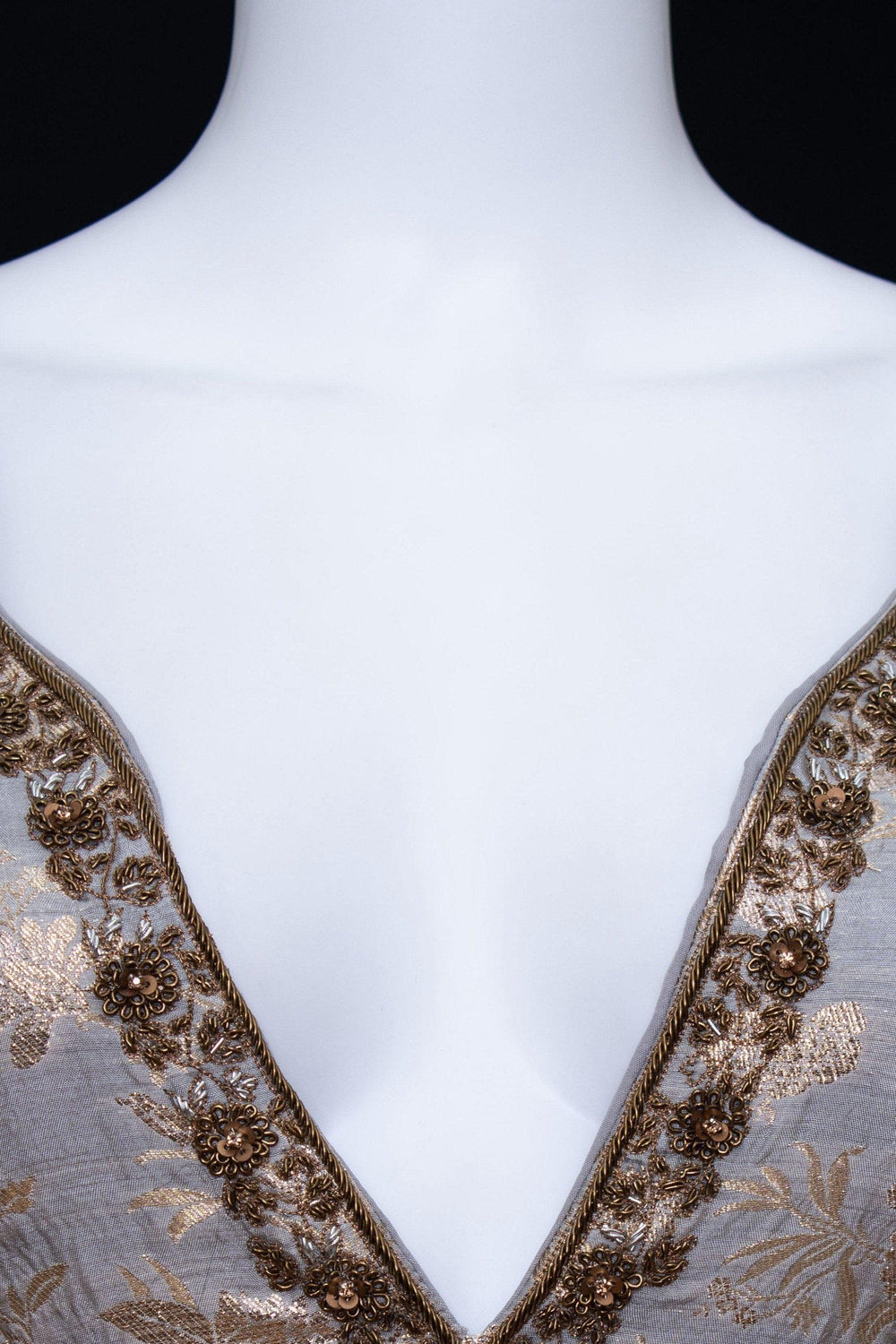 Close-up of a jacquard silk gown with a deep plunge neckline and intricate gold zardoshi hand embroidery.