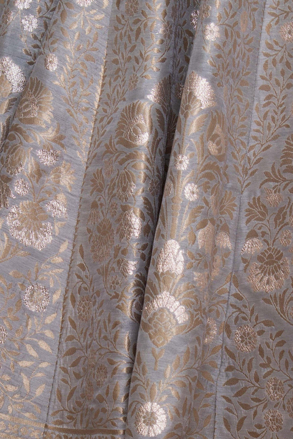 Close-up of green jacquard silk fabric with intricate gold floral woven patterns and subtle folds.