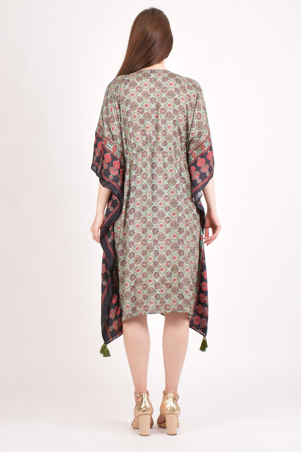 Back view of a woman wearing a green Ajrakh print muslin silk kaftan with floral embroidered sleeves and tassels.