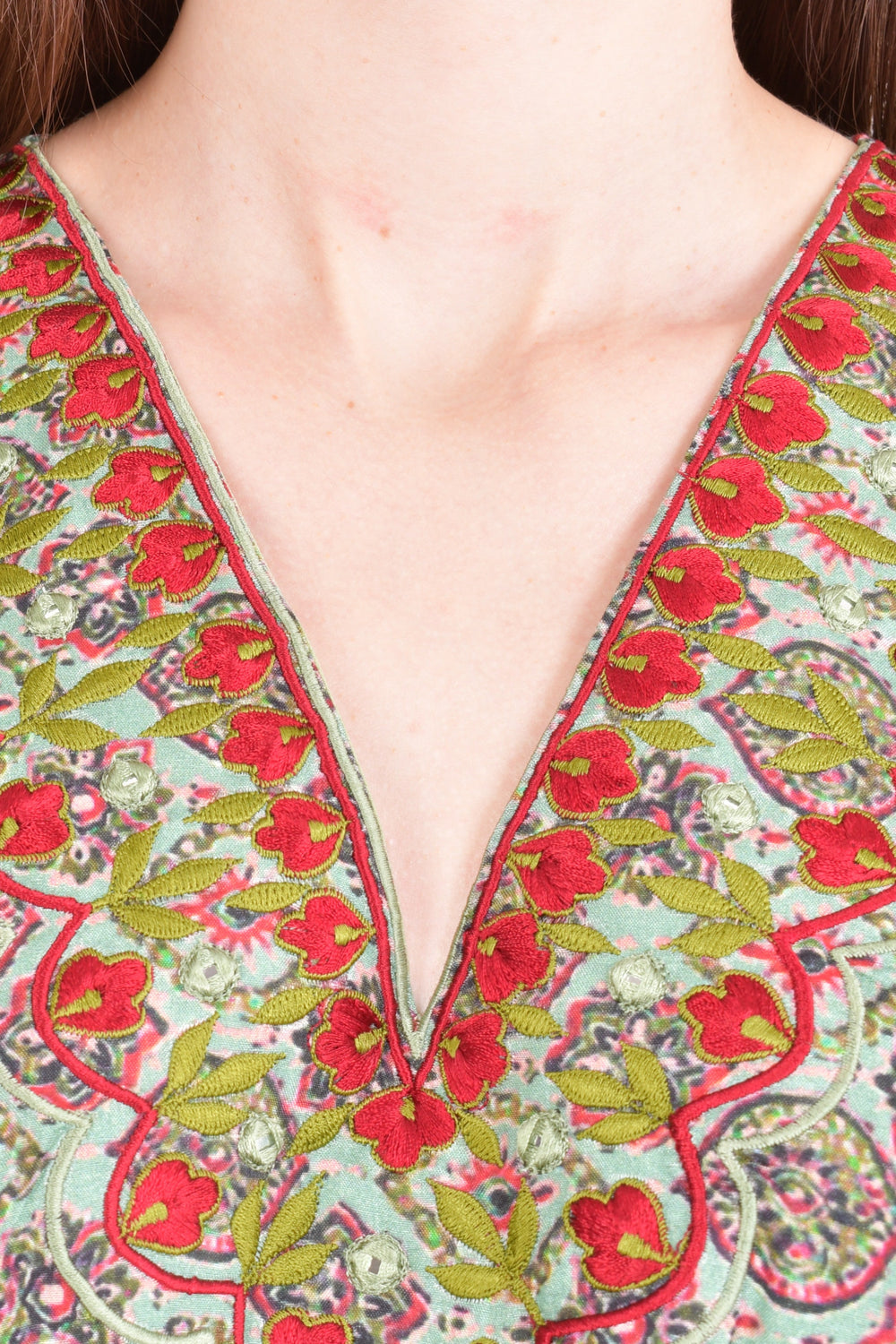 Close-up of a green muslin silk Ajrakh print kaftan with red floral resham embroidery on the V-neckline.