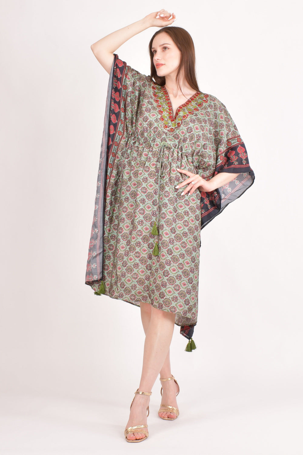 Woman models a green muslin silk Ajrakh print kaftan with embroidered V-neck and drawstring waist.