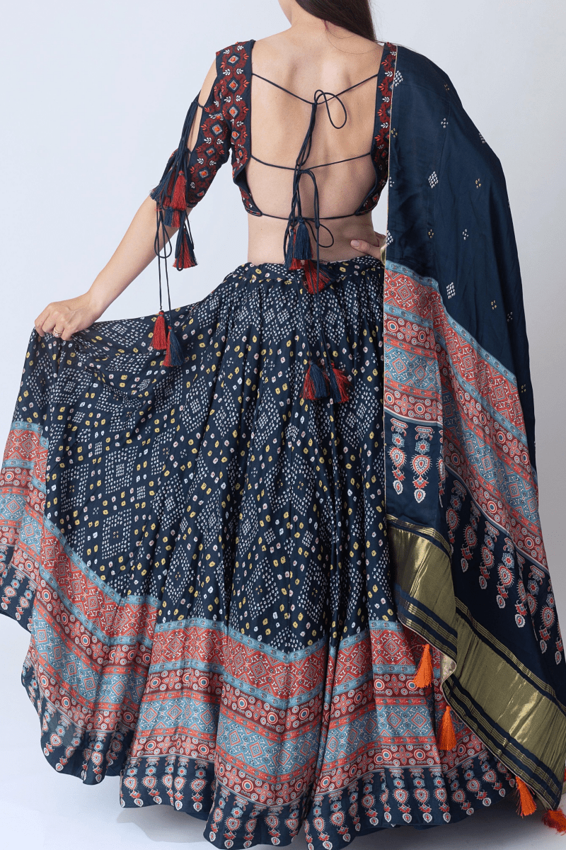Woman in a dramatic twirl, showcasing a navy Bandhani & Ajrakh print silk lehenga choli with tie-back blouse and dupatta.