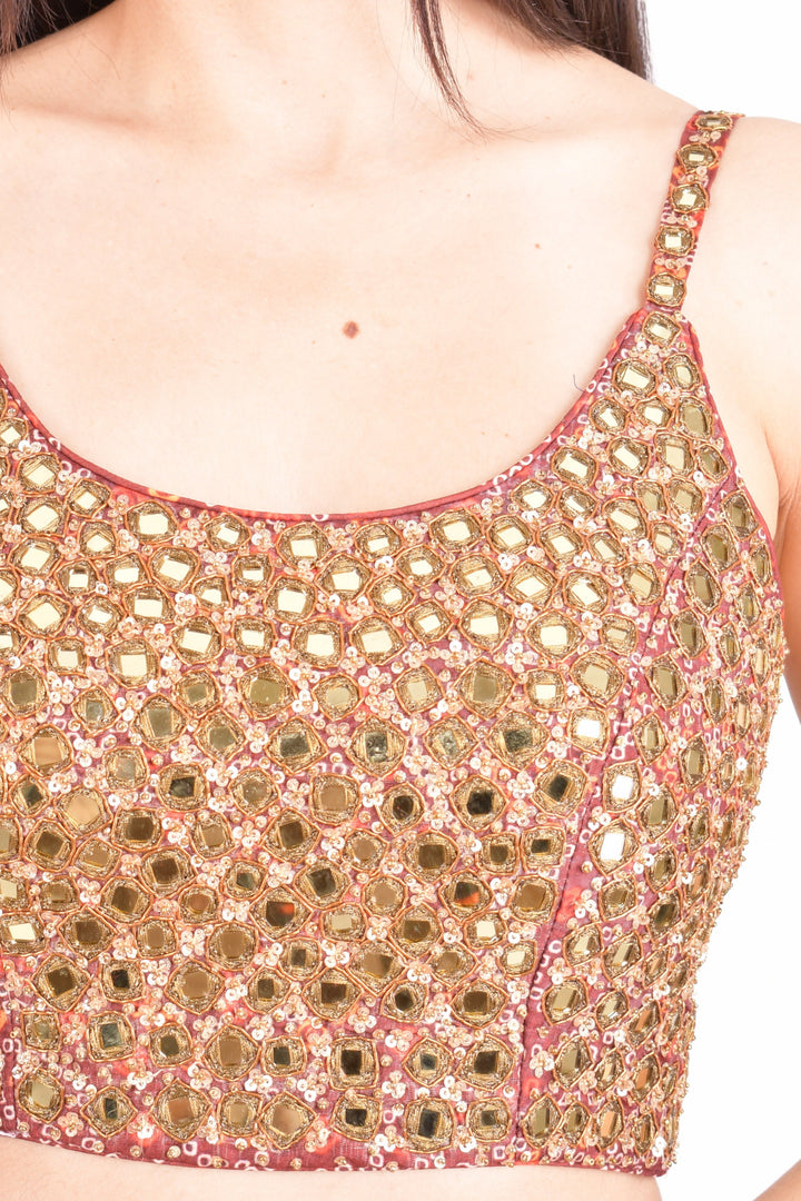 Close-up of a sleeveless, hand-embroidered silk blouse with all-over mirror work in a dramatic Garba style.
