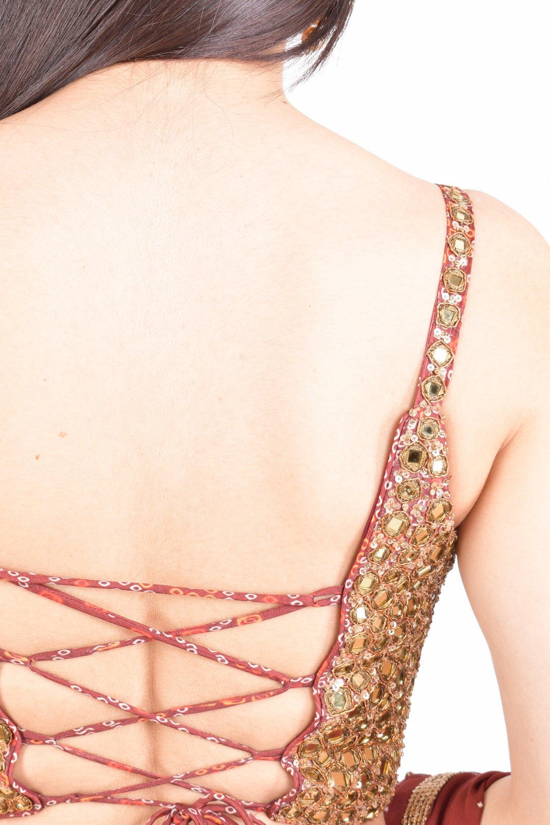 Back of a woman in a gold and red hand-embroidered Chaniya Choli blouse with a lace-up back.