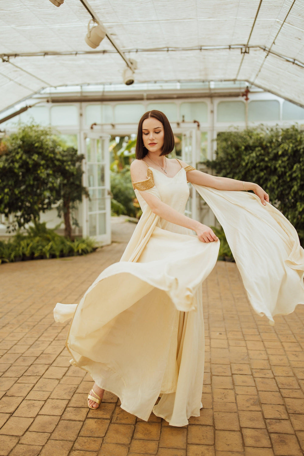 Beige silk long dress with caped sleeves and flowing skirt, worn by a woman.