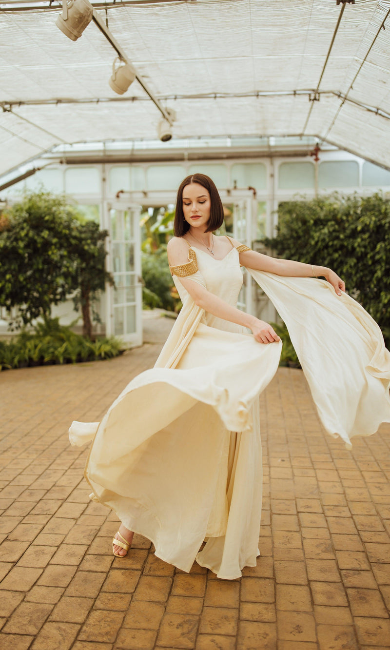 Beige silk long dress with caped sleeves and flowing skirt, worn by a woman.