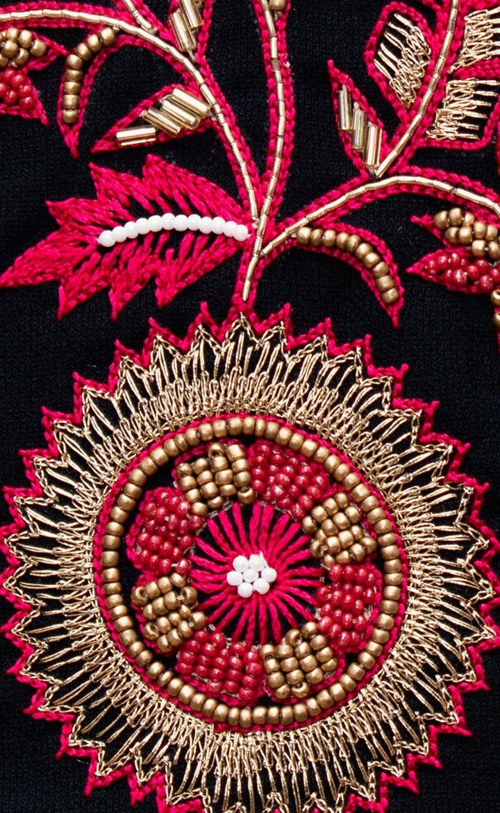 Close-up of black silk chaniya choli with intricate gold, red, and white bead and thread embroidery.