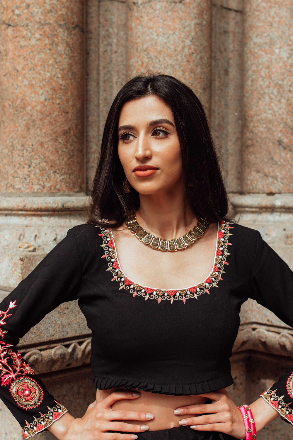 Woman in black silk chaniya choli with gold butta, intricate pearl, bead, and thread embroidery, and gold necklace.
