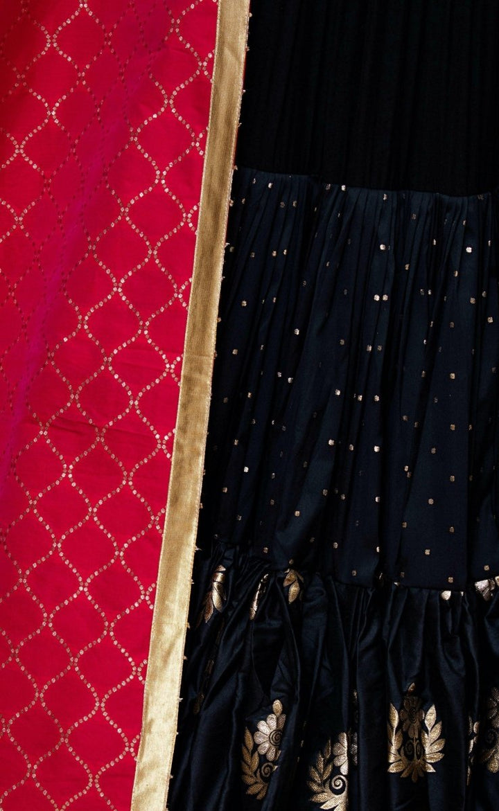 Black silk chaniya choli with gold butta motifs and a contrasting red dupatta with gold lattice print.