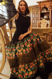 Black high-neck gown with vibrant floral embroidery on the skirt, worn by a model.