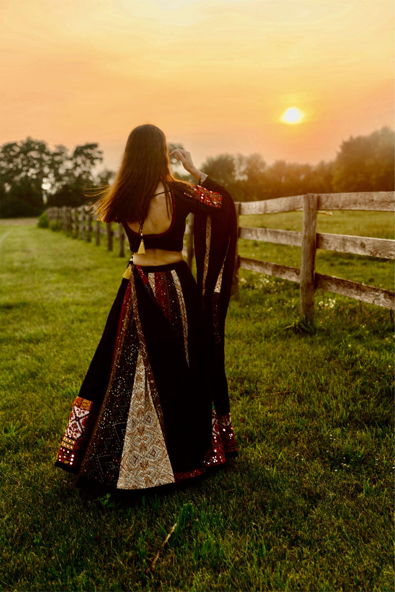 Andes Black silk lehenga choli set with multi-colored panels, embroidered borders, and U-back blouse, in a dramatic twirl at sunset.