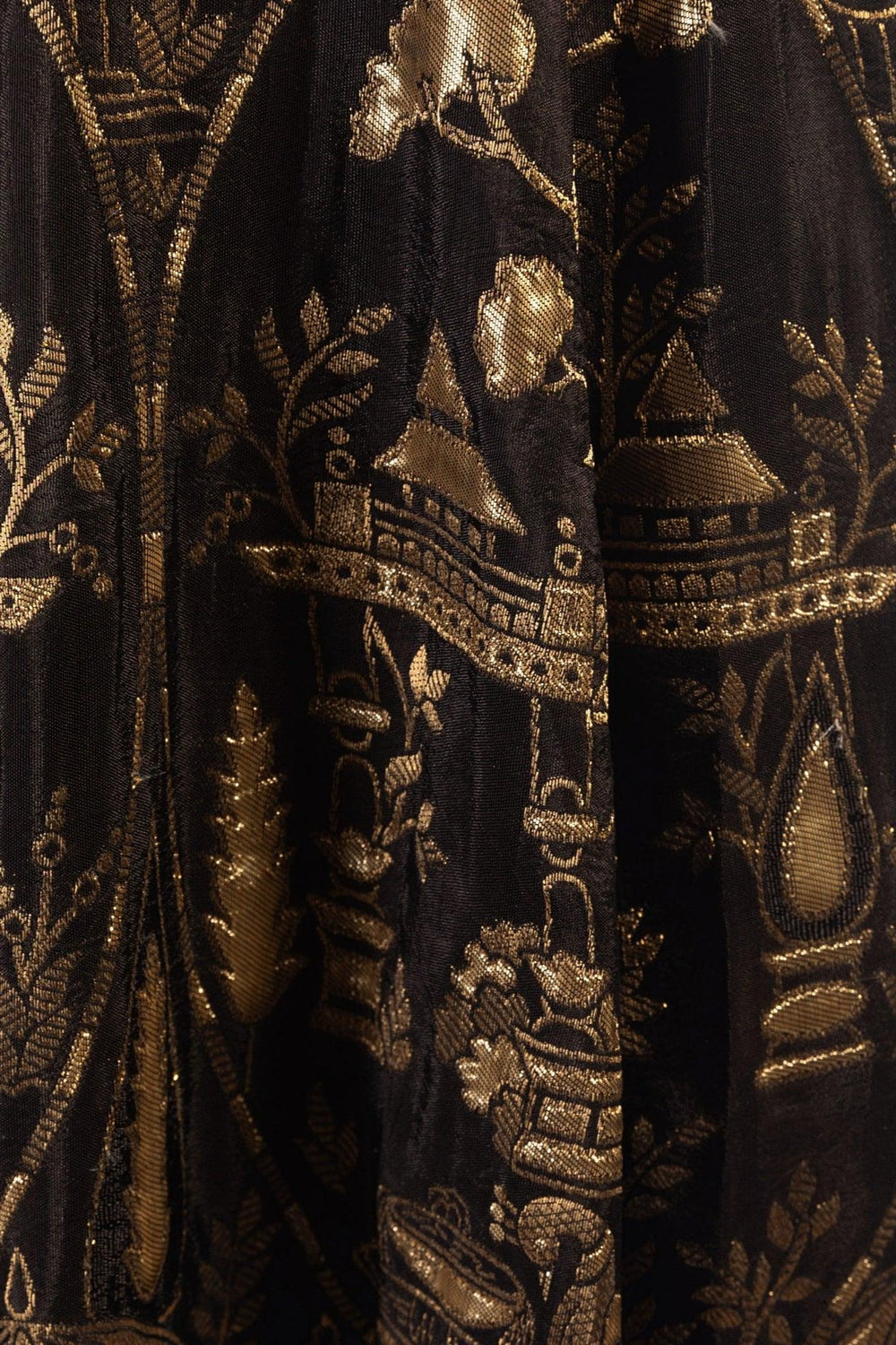Close-up of black jacquard silk with intricate golden patterns.