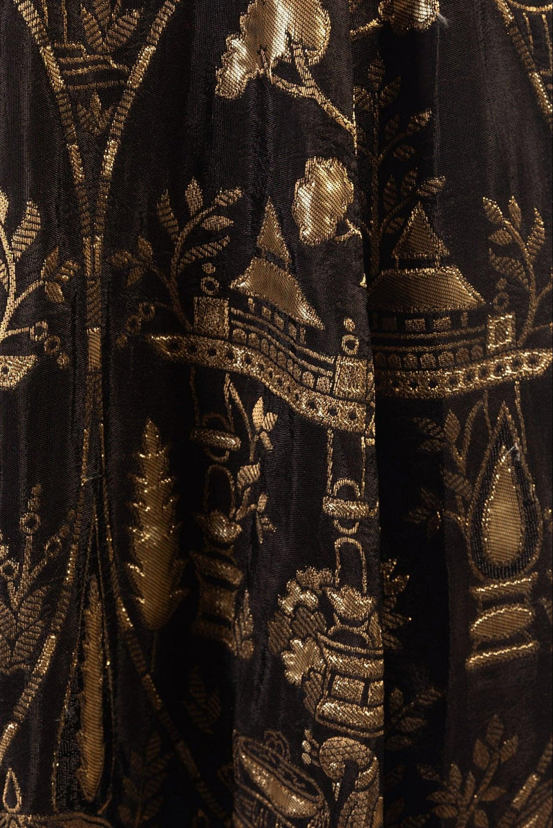 Close-up of black jacquard silk with intricate golden patterns.