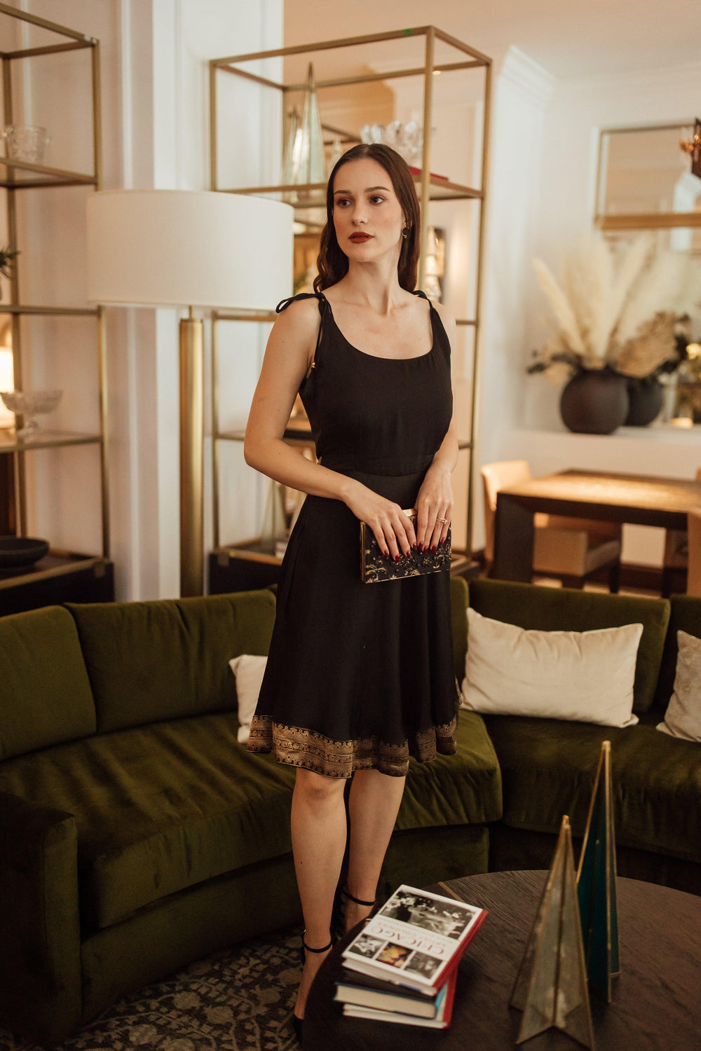 Black silk mini dress with Banarasi silk hem, sleeveless, and a golden bow tie at the back.