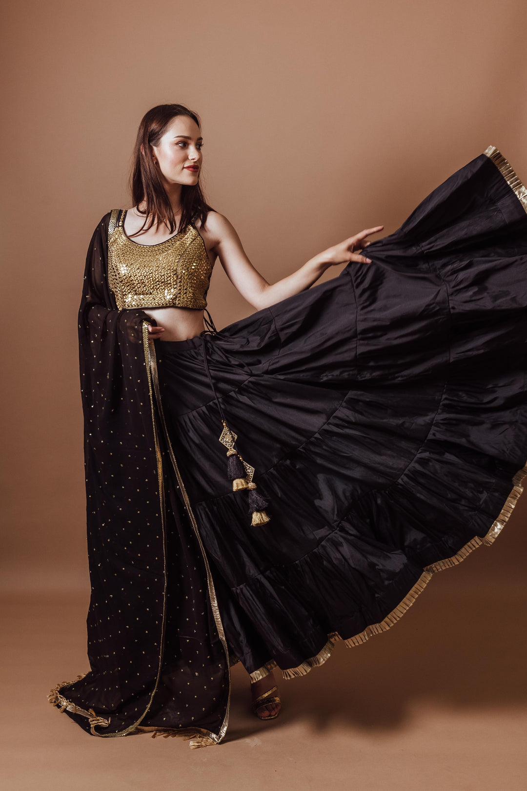 Victoria Black and Gold Lehenga Set: woman in sleeveless, mirror-embroidered blouse and flowing black silk lehenga.