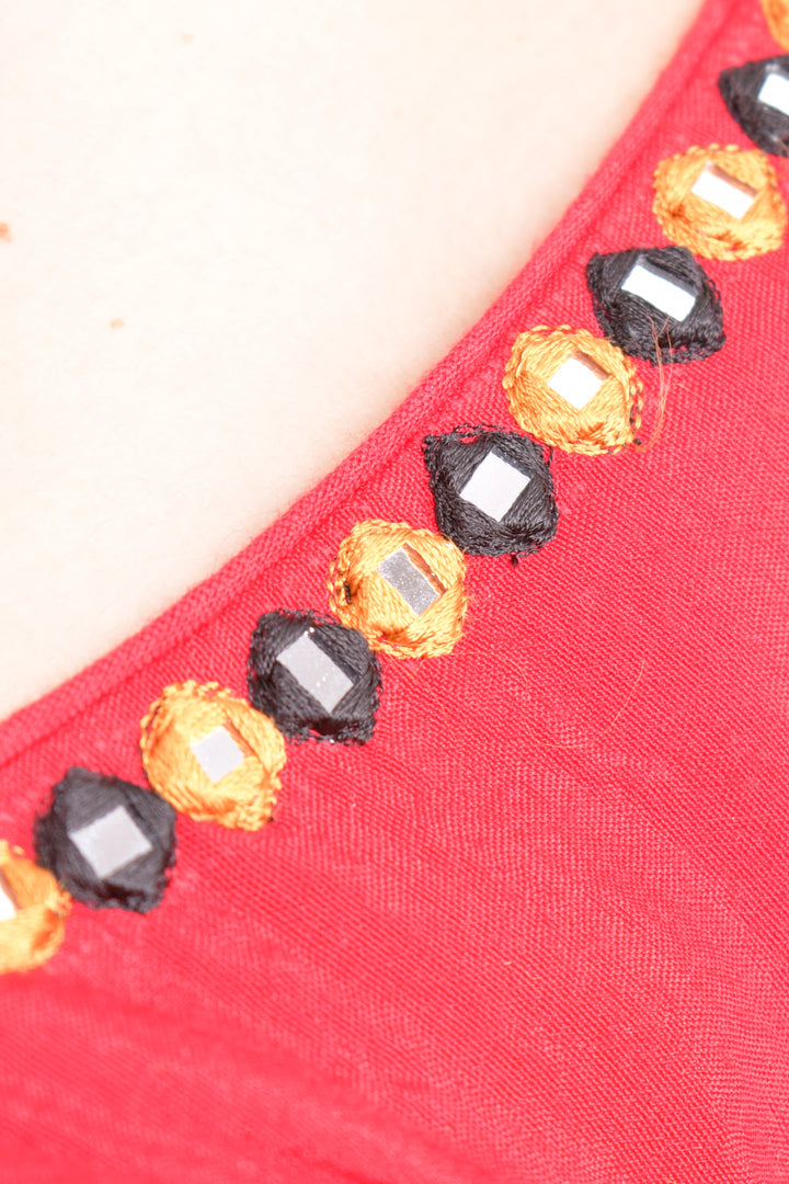 Close-up of a red cotton blouse with embroidered neckline and mirror work, ideal for Garba.