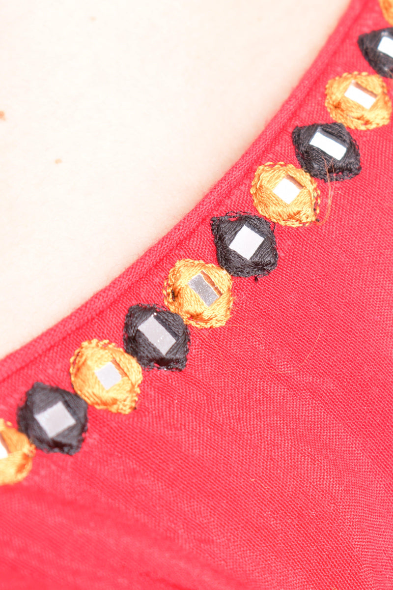 Close-up of a red cotton blouse with embroidered neckline and mirror work, ideal for Garba.