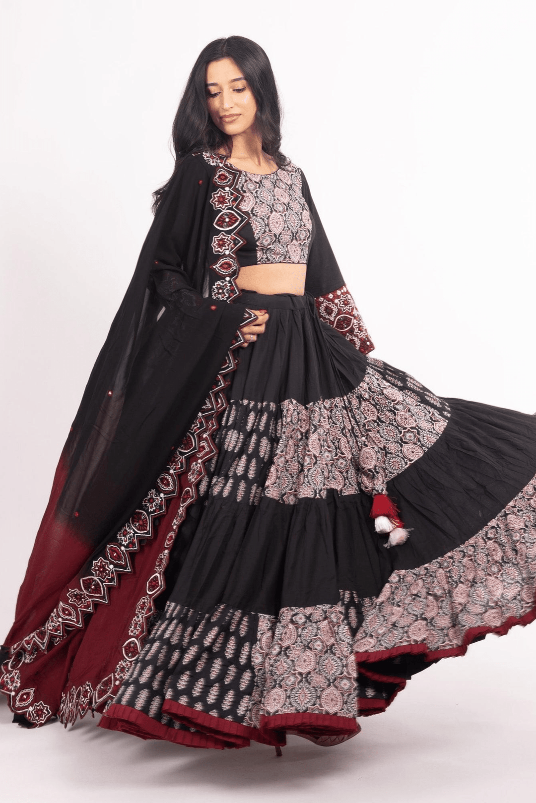 Woman in a black and red flared tiered silk lehenga choli set, perfect for Garba.