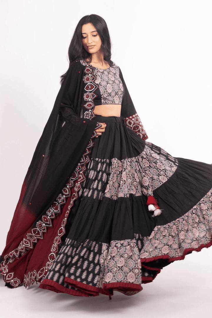 Woman in a black and red flared tiered silk lehenga choli set, perfect for Garba.