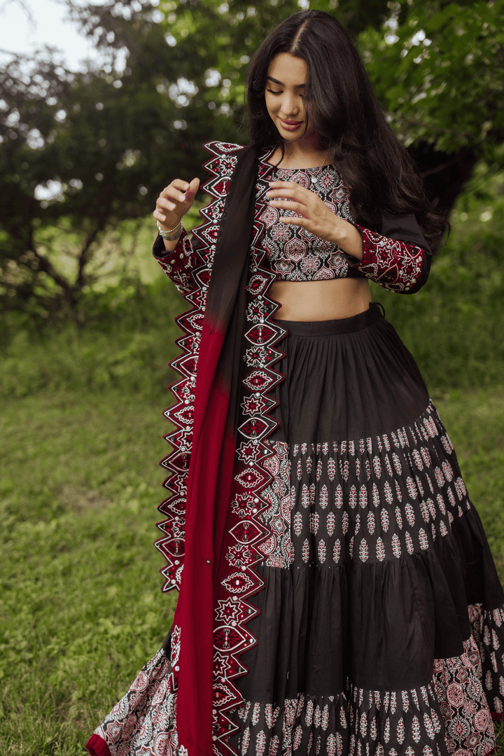 Black and red tiered silk lehenga choli with intricate embroidery, perfect for Garba and festive occasions.