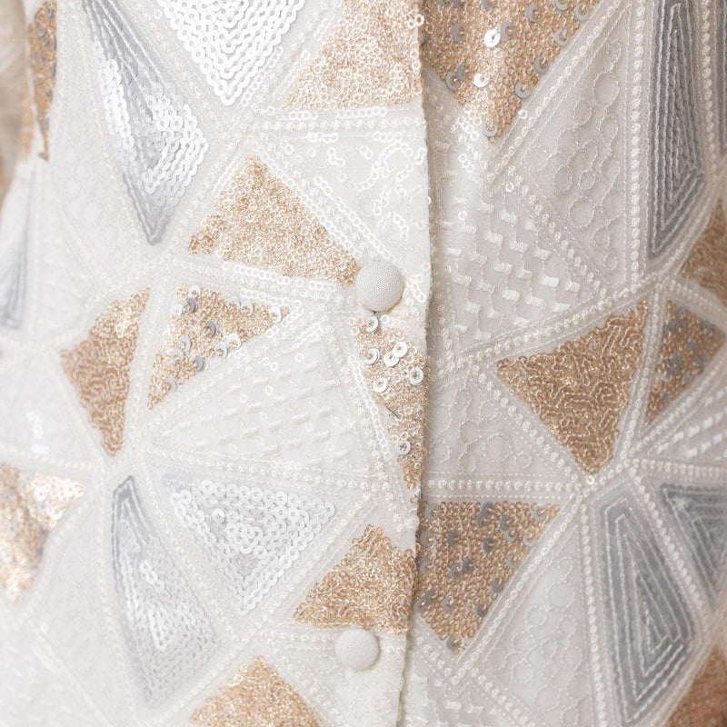 White blazer dress with all-over gold and silver sequin geometric patterns and white buttons.