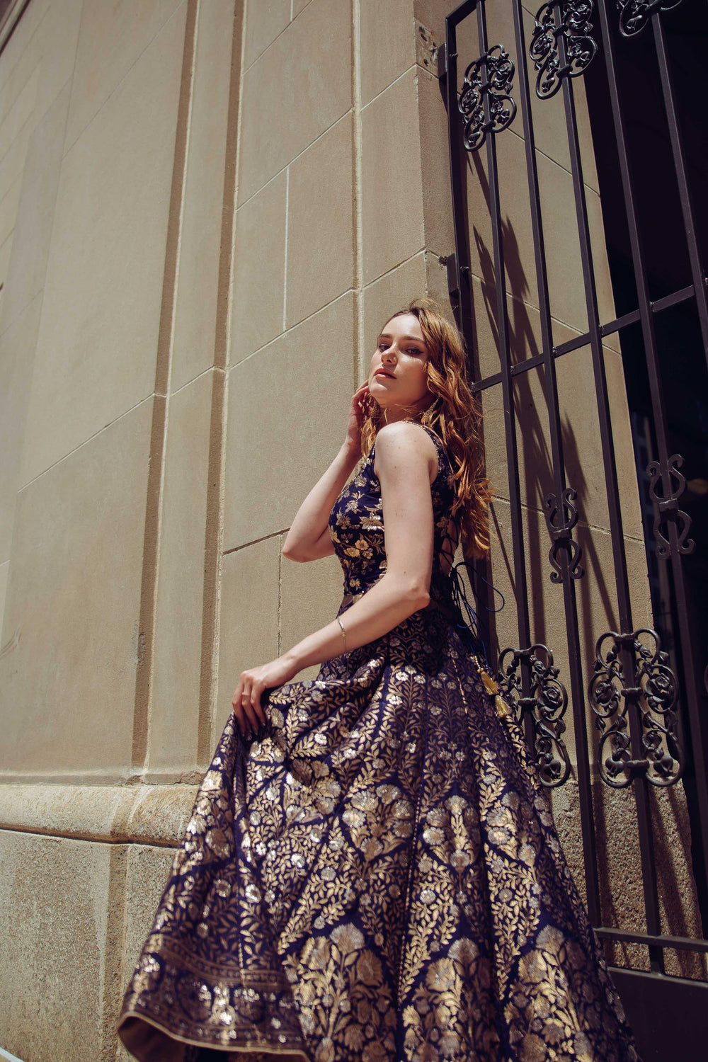 Model in a blue Banarasi jacquard silk A-line gown with gold patterns and a hand-embroidered neckline.