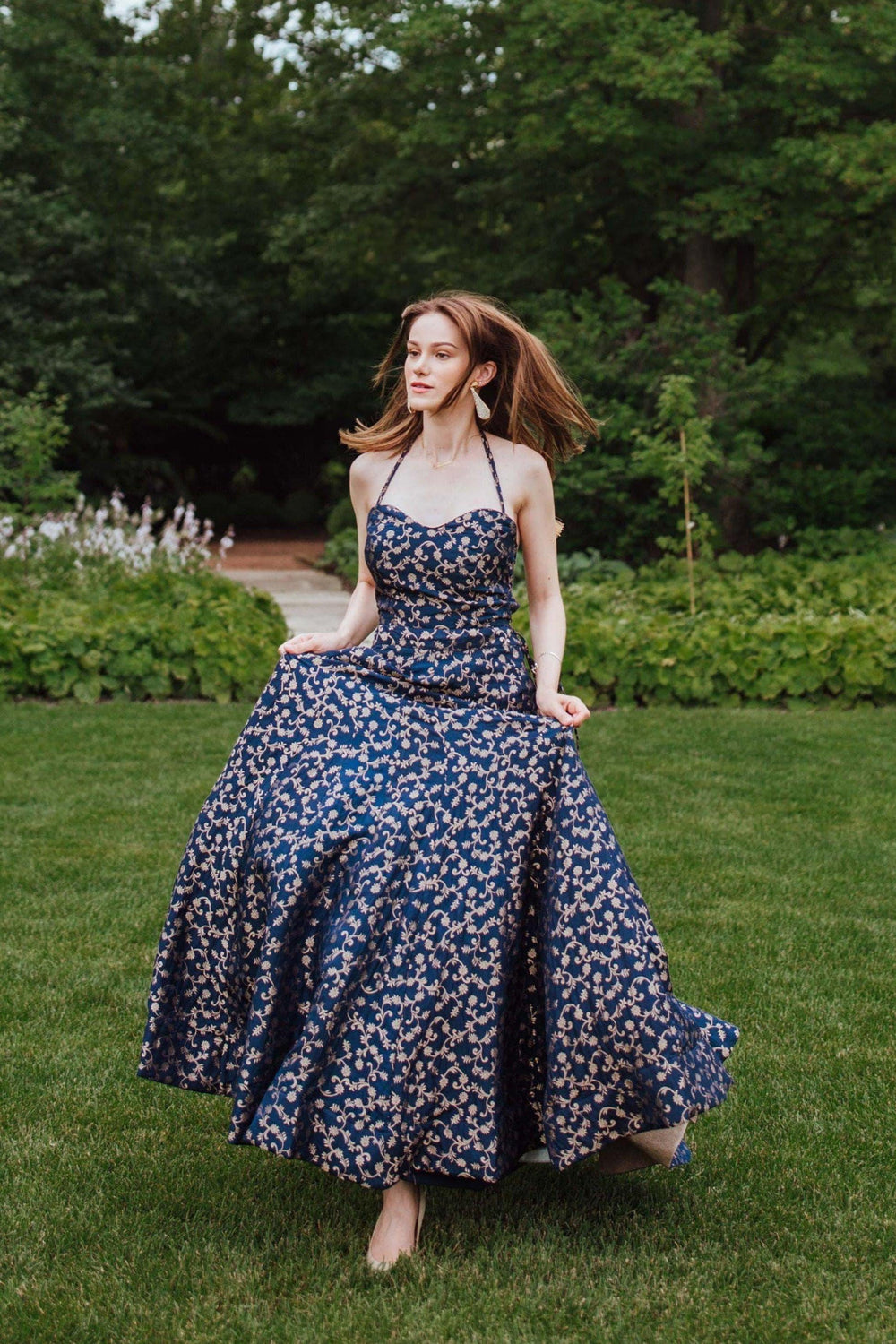 Blue silk brocade convertible A-line gown with intricate weaving, worn by a woman in a garden.