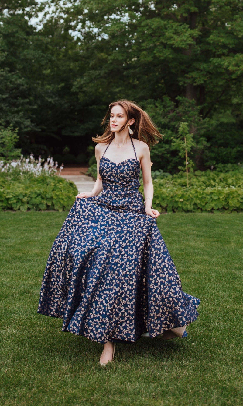 Blue silk brocade convertible A-line gown with intricate weaving, worn by a woman in a garden.