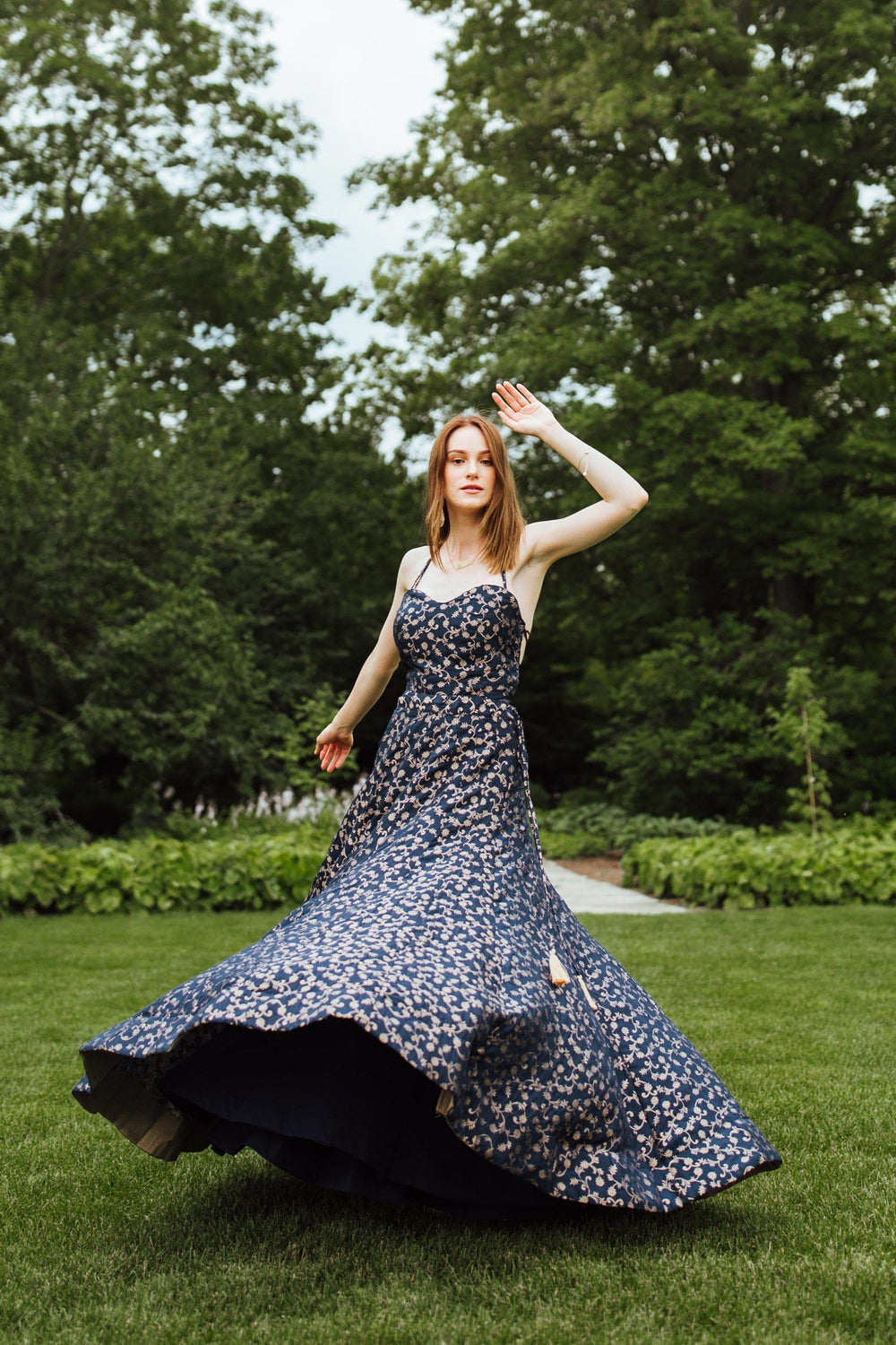 Blue silk brocade convertible gown with A-line flare, worn by a model in a garden.