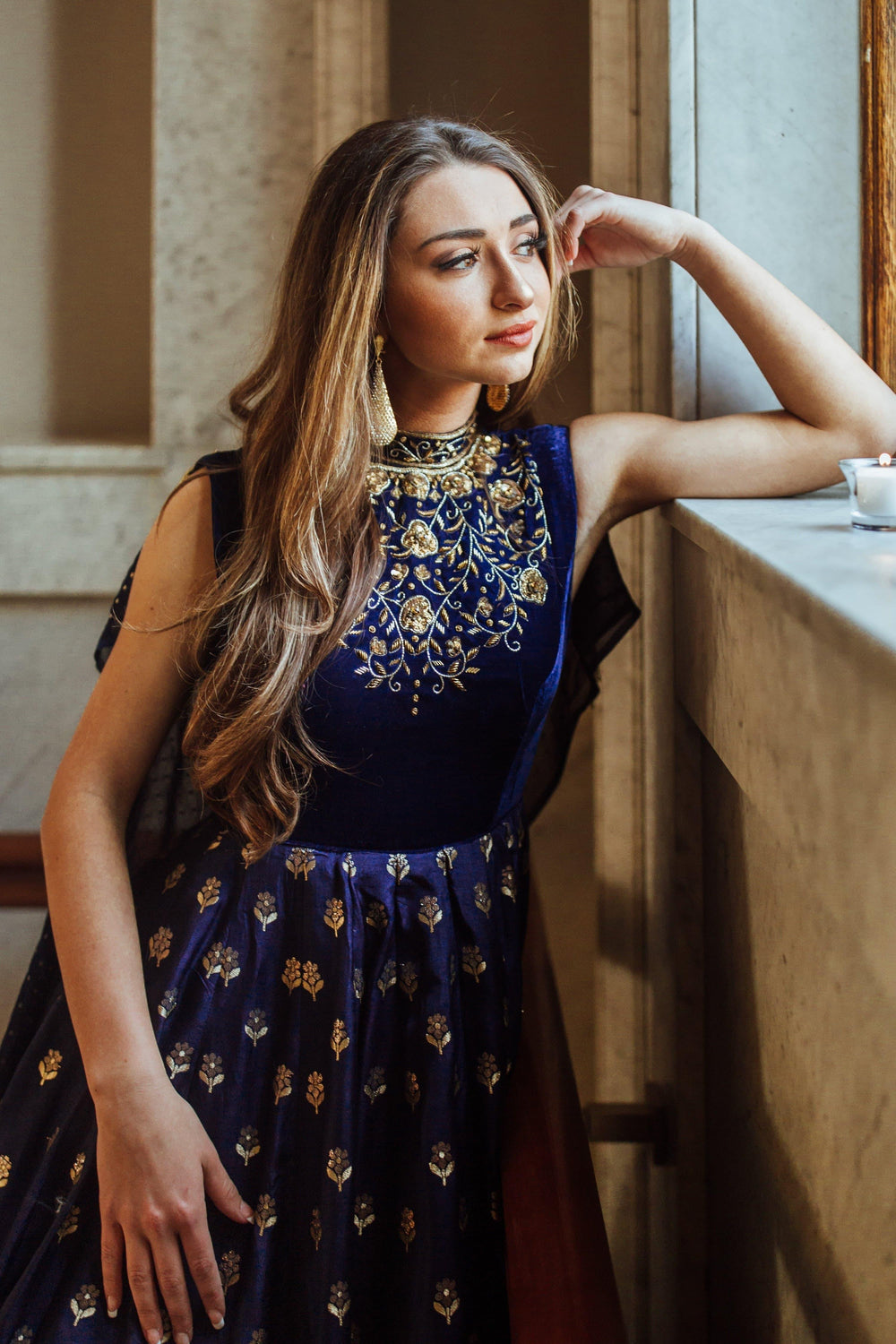 Blue velvet and Banarasi silk gown with gold hand embroidery, high neckline, and jacquard hem.