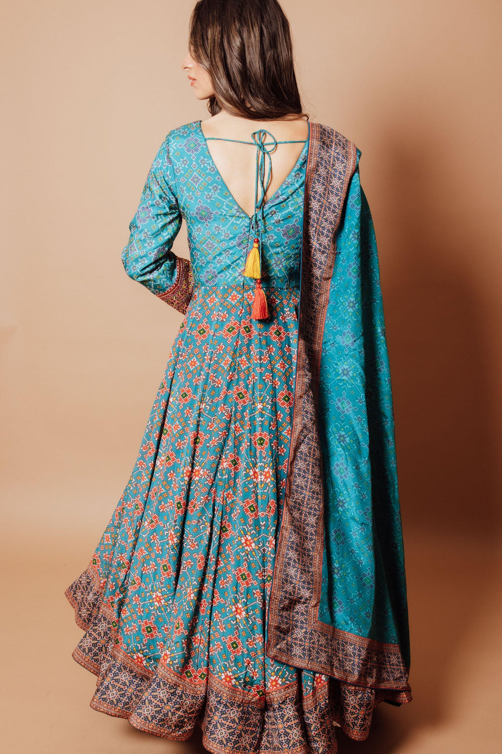Blue silk patola print gown with integrated drape, resham embroidery, long sleeves, and back string tie.