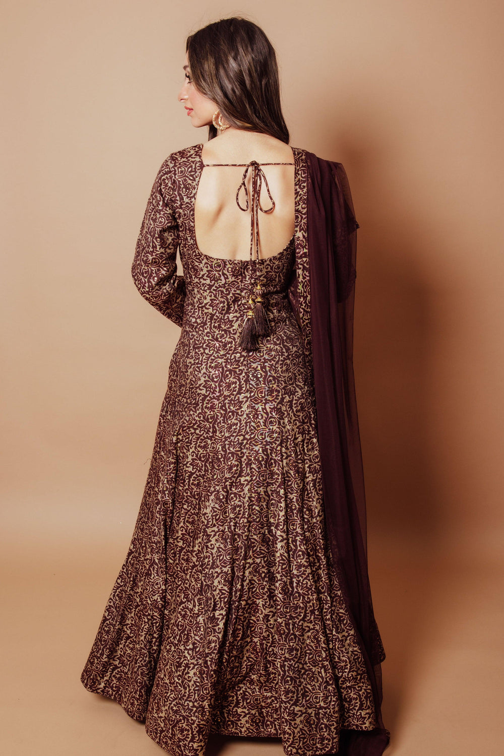 Brown A-line gown with gold scrolling vine embroidery, deep back, and wine net drape.