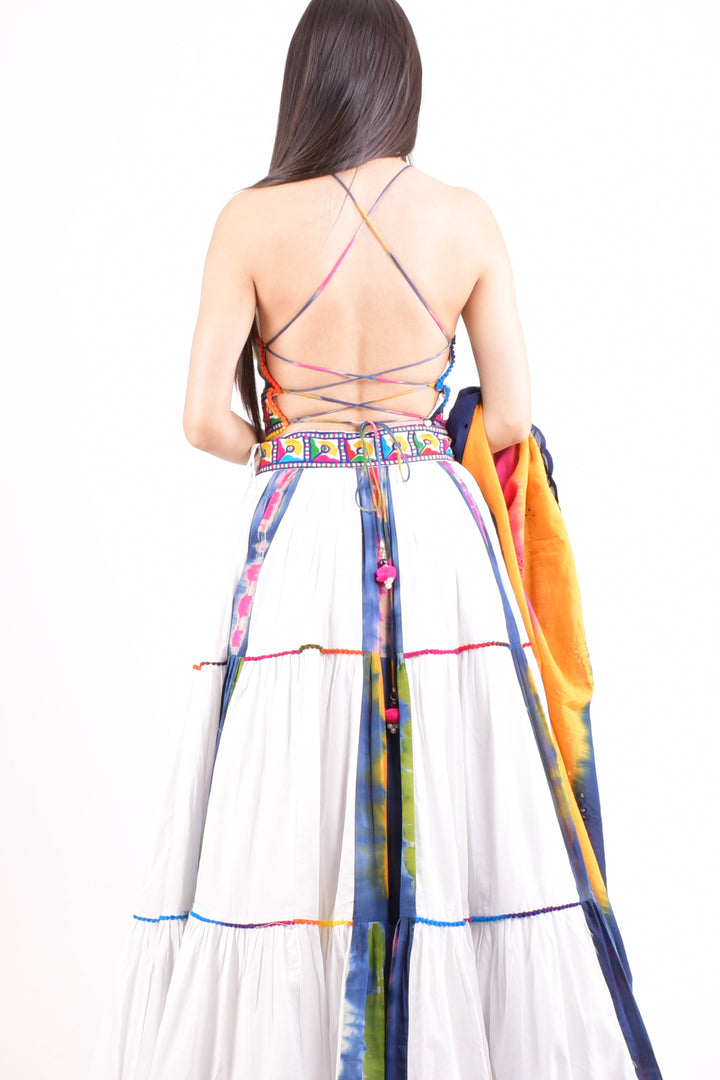 Cotton tie-dye Chaniya Choli, mirror-work blouse, tiered white skirt with colorful panels, pom-poms, Garba style.