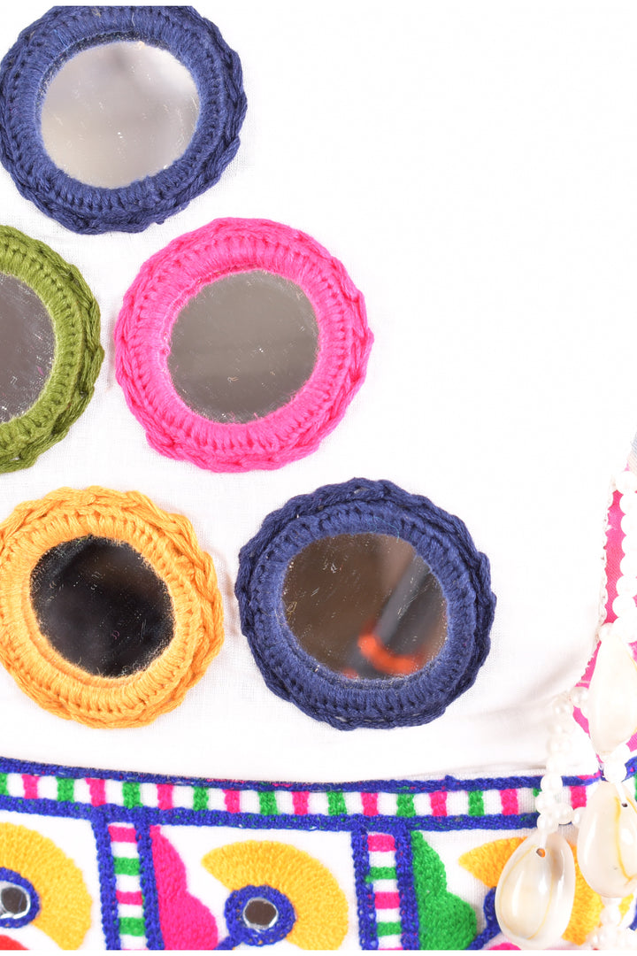 Close-up of vibrant mirror-work embroidery on a white cotton Chaniya Choli, featuring colorful yarn borders.
