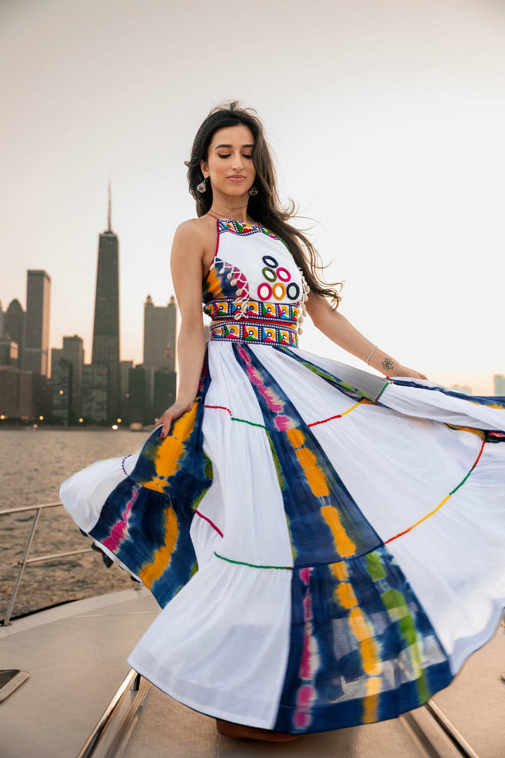 Woman in a white cotton tie-dye Chaniya Choli with mirror work blouse, dramatically twirling on a boat.