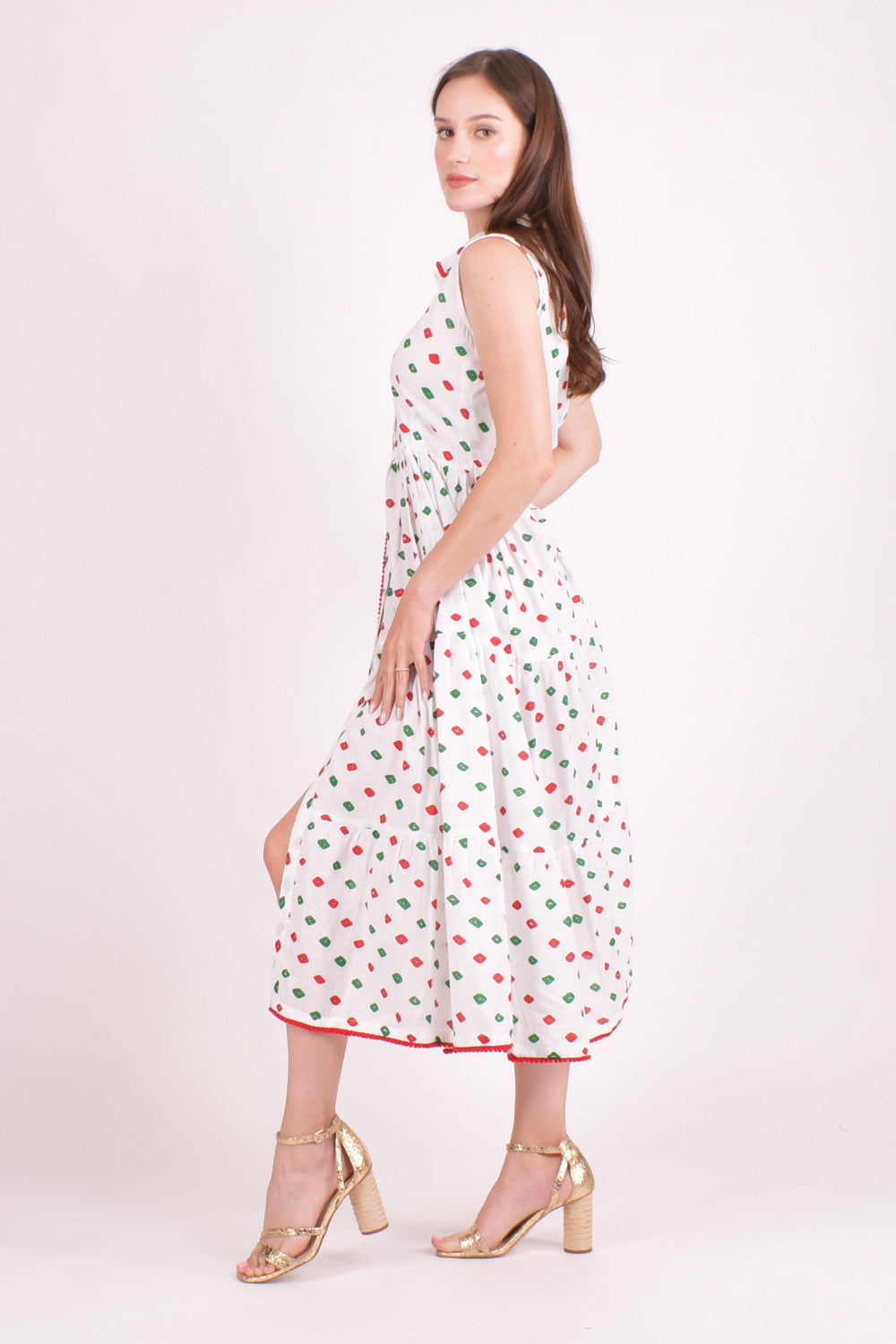 White cotton tiered midi dress with red and green dots, pom-pom trim, and a left leg slit.