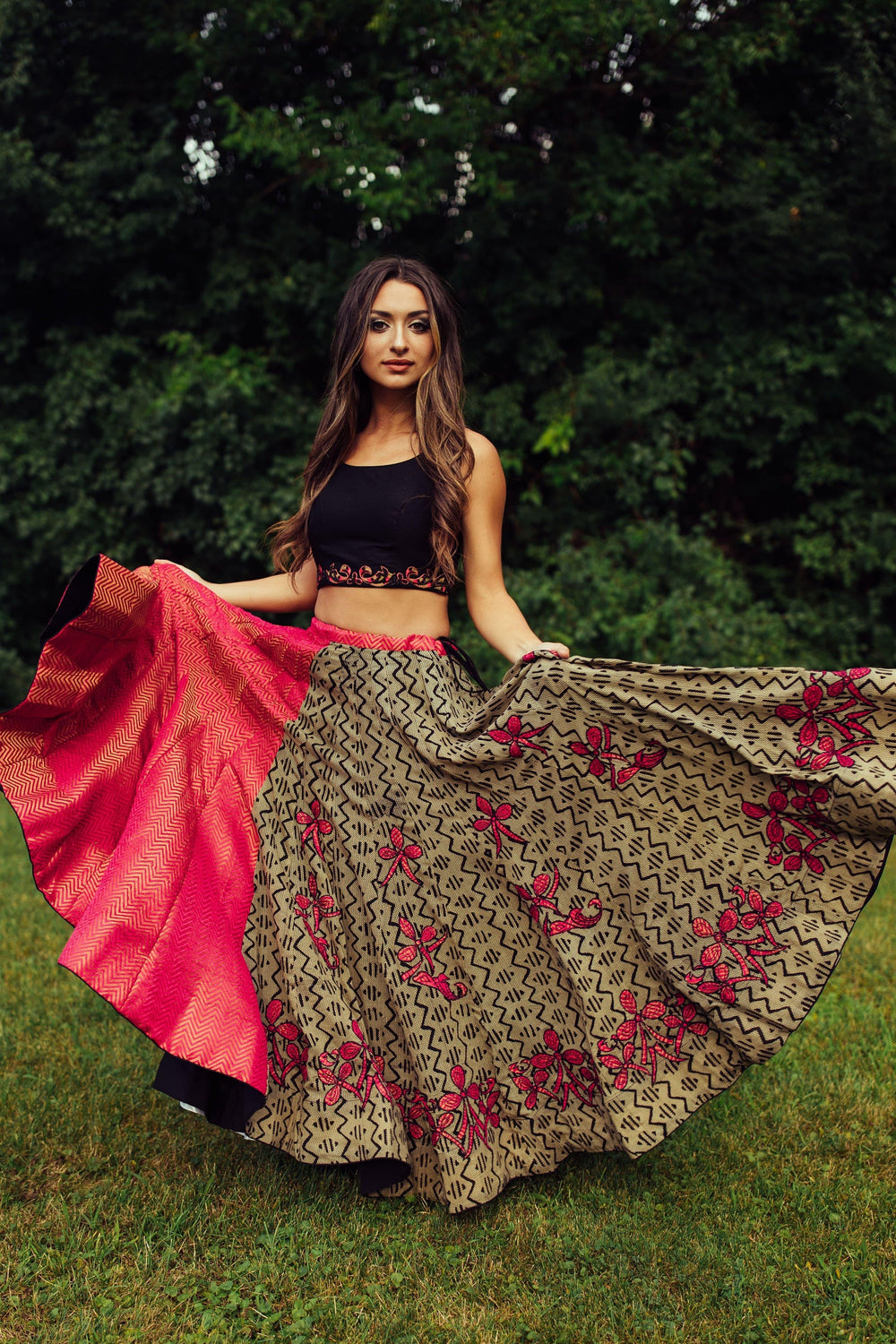 Woman in embroidered multicolor cotton-silk chaniya choli, twirling the skirt to show its vibrant design.