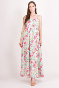 Model wearing a floral tiered maxi dress in light blue hakoba cotton with pink floral motifs and eyelet embroidery.