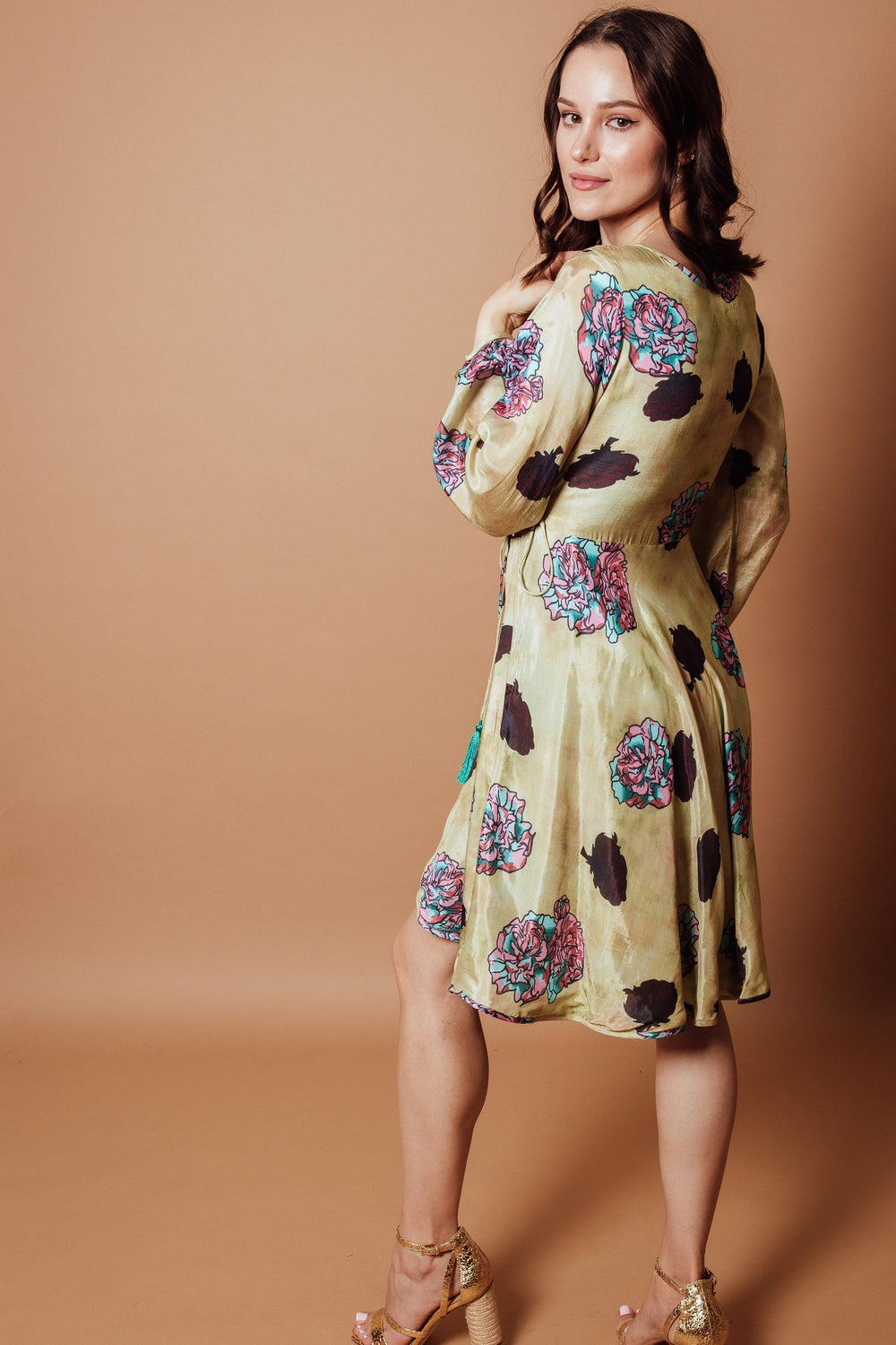 Green silk floral wrap dress with full sleeves and side closure, modeled by a woman.