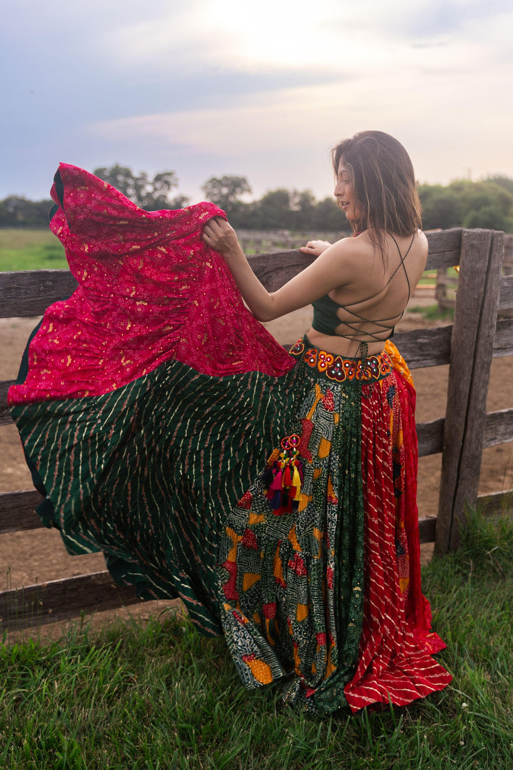 Woman in a full flare multicolor cotton Chaniya Choli with green tie-back top, dramatic twirl, and Garba style.