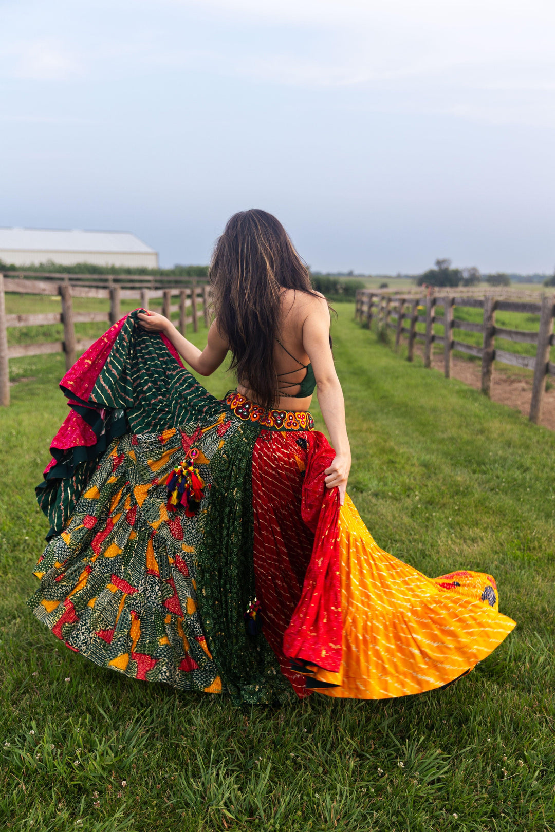 Woman in a full flare multicolor cotton Chaniya Choli, green tie-back top, and dramatic twirl.
