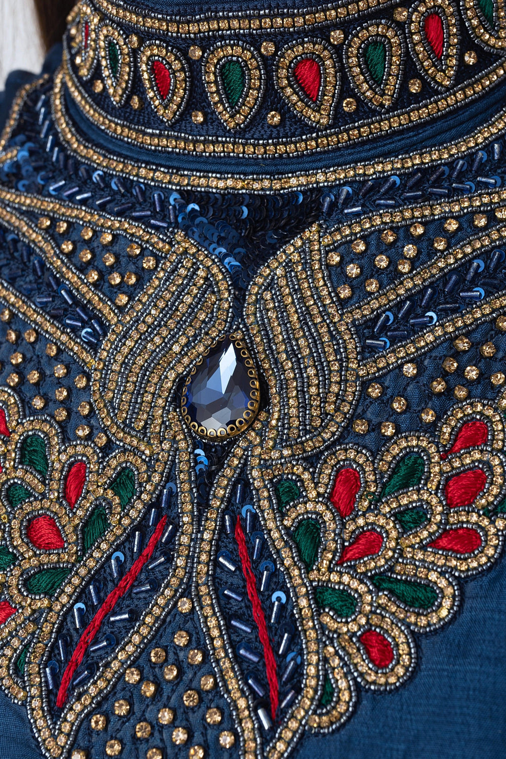 Navy raw silk gown with intricate gold, red, and green hand embroidery and a central blue gemstone.