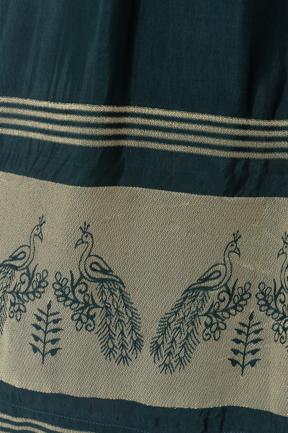 Close-up of a green viscose dress with a golden jacquard peacock-weaved border.