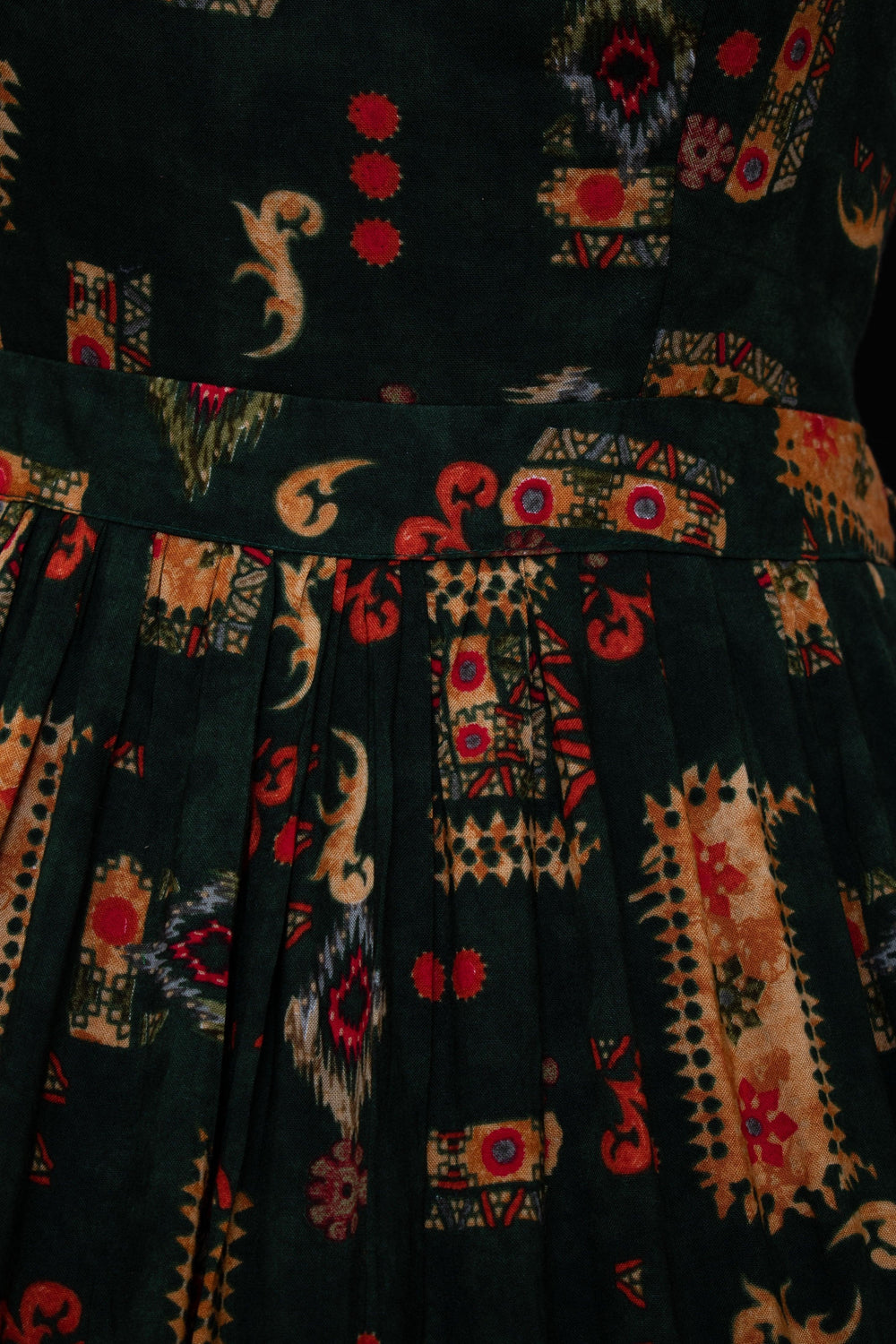 Green rayon maxi gown with orange, gold, and red ethnic motif print, sweetheart bodice, and cinched waist.