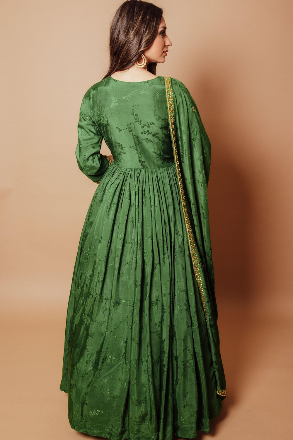 Emerald green silk anarkali gown with tonal floral hand embroidery, gold accents, and matching drape.