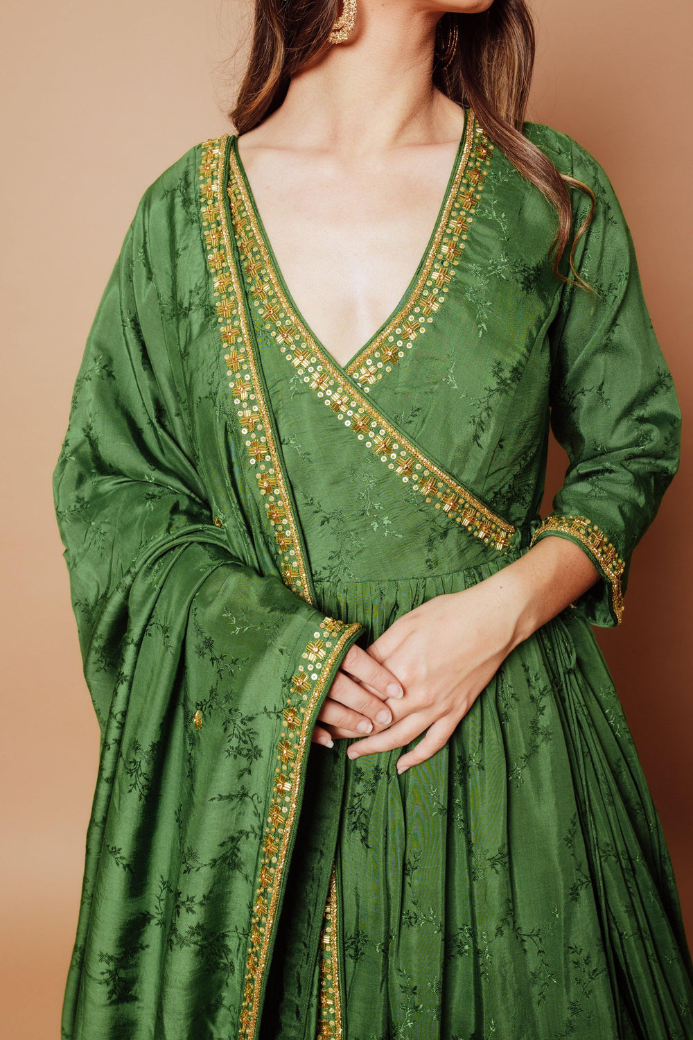 Emerald green silk anarkali gown with gold cutdana, stone, and sequin hand embroidery on neckline, cuffs, and drape.