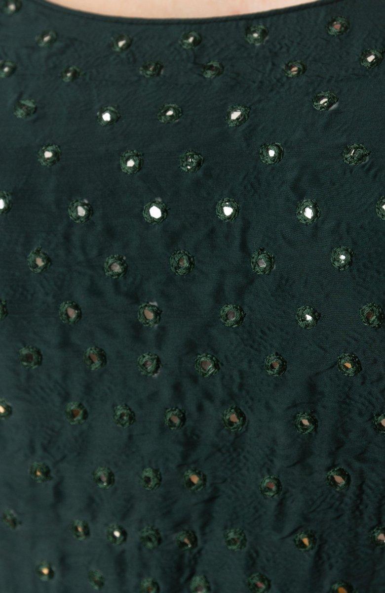 Close-up of a dark green silk gown with intricate mirror embroidery.
