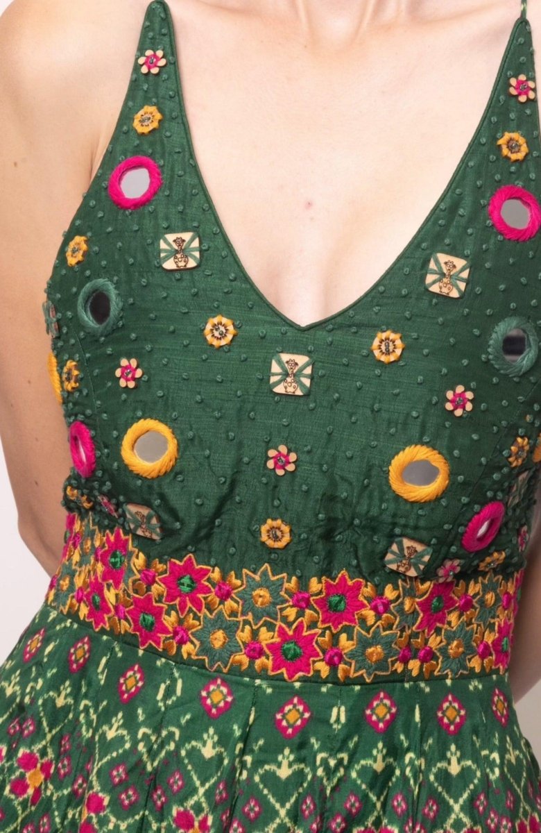 Green silk halter dress with hand-embroidered torso, mirror work, and patola patterns.