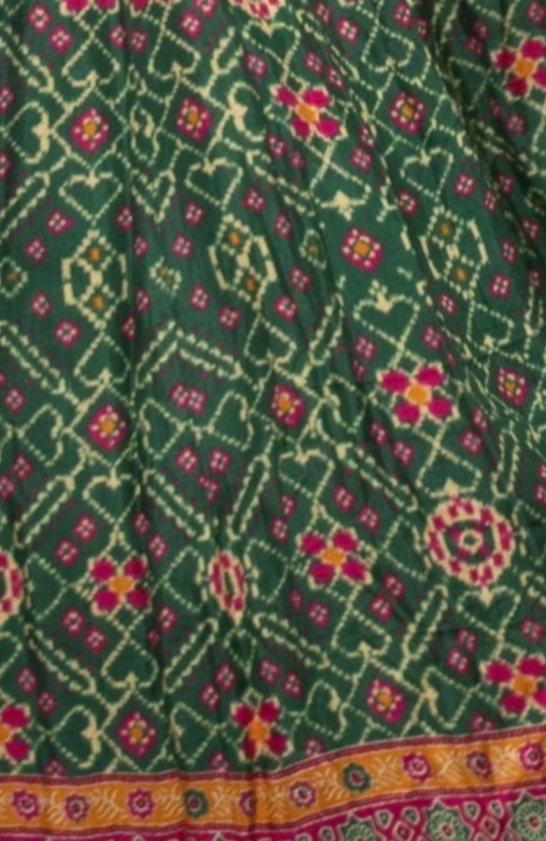 Green silk gown with intricate pink and yellow patola patterns and an embroidered border.